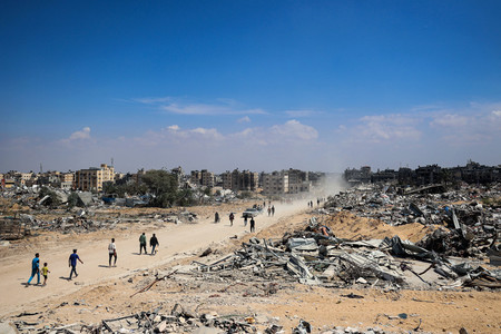 ７日、パレスチナ自治区ガザ南部ハンユニスで、イスラエル軍が撤退した街を歩く人々（ＡＦＰ時事）