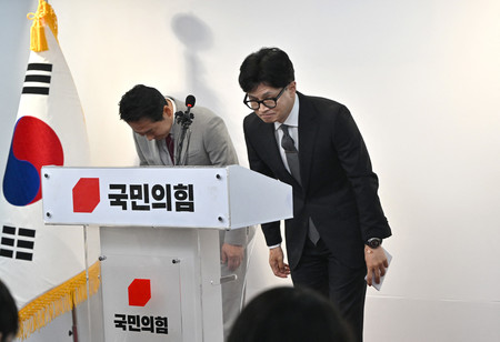 １１日、ソウルで行われた記者会見で頭を下げる韓国与党「国民の力」トップの韓東勲非常対策委員長（右）（ＡＦＰ時事）