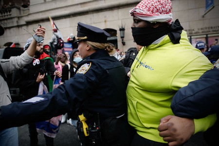 １８日、米ニューヨーク市のコロンビア大でデモの参加者を逮捕する市警の警察官（ＡＦＰ時事）