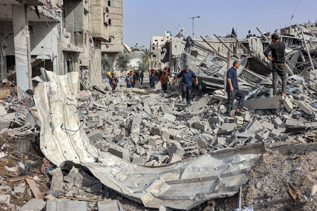 １８日、パレスチナ自治区ガザ北部のガザ市で、イスラエル軍に破壊された建物のがれきの中を歩く人々（ＡＦＰ時事）