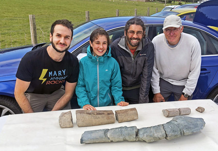 英国で約２億２００万年前の新種魚竜化石（写真手前、顎の骨）を発見した化石愛好家の父娘（同右から２、３人目）（英マンチェスター大提供）