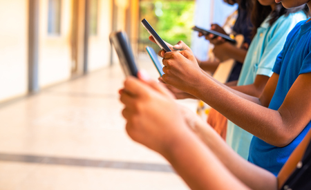 学校でスマートフォンを見る子どもたち（写真はイメージ）