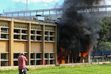 ２５日、ナイロビで、反増税デモのさなかに炎上するケニア議会の建物（ＥＰＡ時事）