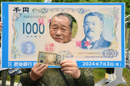 新千円札を手に笑顔を見せる穴井栄次さん＝３日午後、熊本県小国町の北里柴三郎記念館