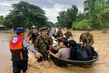 ミャンマーの警官と軍人に救助される住民＝１３日、ネピドー郊外（ＡＦＰ時事）