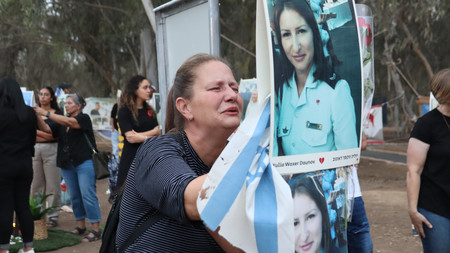 ７日、イスラエル南部レイムで、イスラム組織ハマスに殺害された娘の写真を前に体を震わせて泣く母親