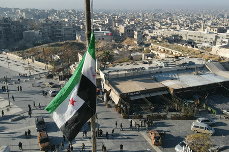 シリア第2の都市アレッポの中心部に掲げられた反体制派の旗=11月30日(AFP時事)