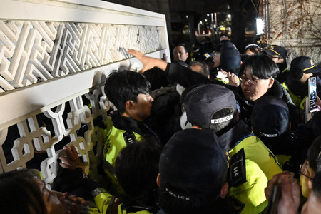 3日夜、ソウルにある韓国国会の正門で人々と押し合う警官(AFP時事)