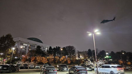 3日夜、ヘリが上空を飛ぶソウルにある韓国国会(EPA時事)