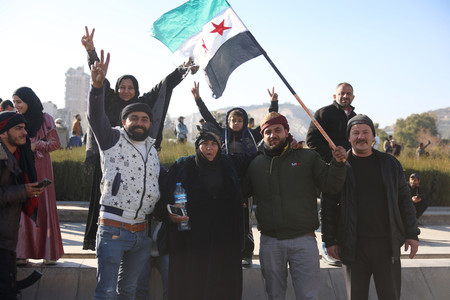 8日、シリアの首都ダマスカスで、反体制派の旗を振る人々(EPA時事)