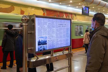 22日、平壌の地下鉄駅に設置されたデジタル画面でトランプ米大統領の就任を報じた労働新聞を読む男性(AFP時事)