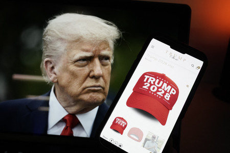 トランプ米大統領の画像と、「トランプ２０２８」と書かれた帽子を販売するウェブサイトを映したスマートフォン＝２４日、ワシントン（ＡＦＰ時事）