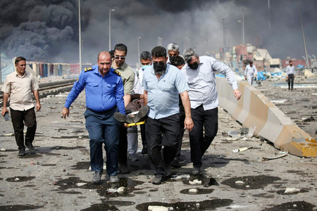26日、大規模な爆発が起きたイラン南部バンダルアバスの港湾地区で、負傷者を搬送する人々(AFP時事)