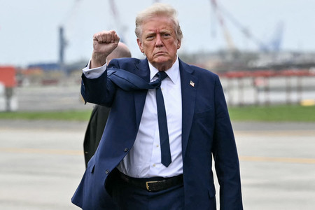26日、米東部ニュージャージー州の空港で、報道陣にガッツポーズをするトランプ米大統領(AFP時事)