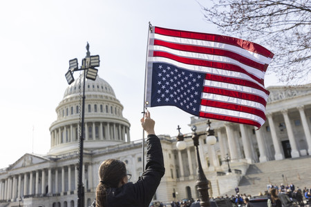 ワシントンの米連邦議会前で、星条旗を逆さに掲げて抗議する市民=3月4日(EPA時事)
