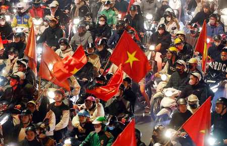 ハノイの路上で国旗を掲げるベトナムのサッカーファンたち＝２０２５年１月６日（ＥＰＡ時事） 