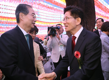 ５日、ソウルで握手を交わす韓国与党「国民の力」大統領選候補の金文洙前雇用労働相（右）と無所属の韓悳洙前首相（ＥＰＡ時事）