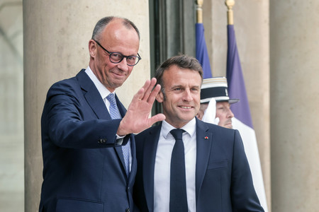 7日、パリのエリゼ宮でドイツのメルツ首相(左)を歓迎するマクロン仏大統領(EPA時事)