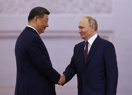 ８日、モスクワのクレムリン（ロシア大統領府）で握手するプーチン大統領（右）と中国の習近平国家主席（ロイター時事）