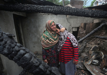 ８日、インドとパキスタンの係争地カシミール地方の村サラマバードで、パキスタン軍の攻撃によって損壊した家屋の中で悲しむ女性ら（ＥＰＡ時事）