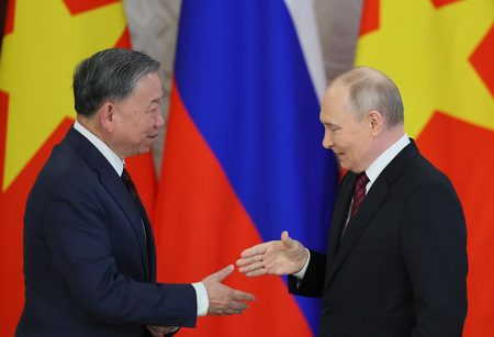 10日、モスクワのクレムリンで、ベトナム共産党のトー・ラム書記長(左)と握手するロシアのプーチン大統領(EPA時事)