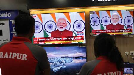 12日、インド東部コルカタの電気店でモディ首相のテレビ演説を見る人たち(EPA時事)