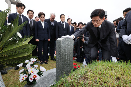 光州事件の犠牲者が眠る国立墓地を参拝する金文洙前雇用労働相(手前右)=17日、韓国南西部・光州市(EPA時事)