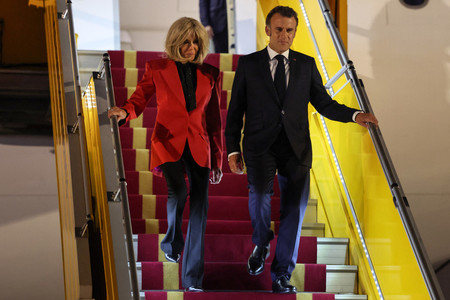 25日、ハノイに到着したフランスのマクロン大統領(右)とブリジット夫人(AFP時事)
