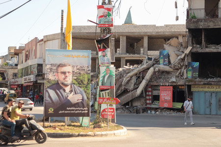 イスラエル軍が昨年１０月の空爆で殺害したレバノン南部ナバティエの市長の写真看板（左）と地方選挙ポスター＝５月２４日