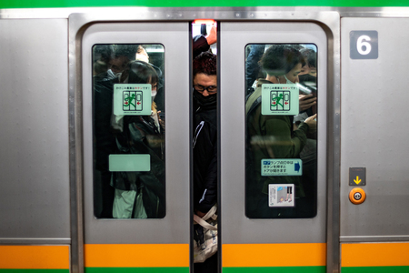東京の新橋駅で電車に乗り込む通勤客ら(資料・AFP時事)
