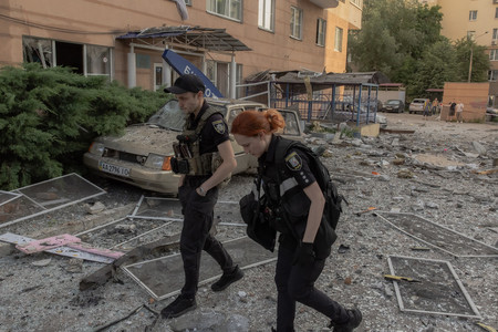 6日、ウクライナの首都キーウで、ロシア軍の攻撃によって被害を受けた住宅街を調べる警察官(AFP時事)
