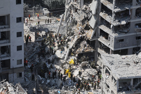 15日、イランの弾道ミサイルが着弾したイスラエル中部テルアビブ近郊の建物崩壊現場で、行方不明者を捜索する治安要員ら(EPA時事)