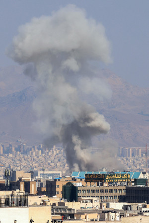 15日、テヘラン中心部で爆発後に立ち上る煙(AFP時事)