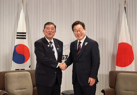 韓国の李在明大統領(右)と握手する石破茂首相=17日、カナダ西部カナナスキス(EPA時事)