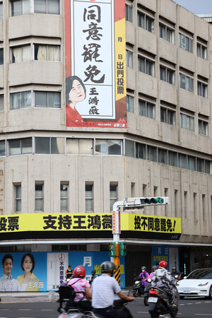 ２０日、台北市で、台湾の国民党立法委員（国会議員）のリコール（解職請求）投票に向け、「罷免同意」を求める看板と罷免への不同意を訴える横断幕が同時に掲げられたビル