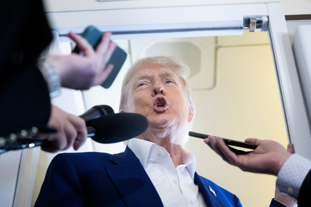 ２４日、米大統領専用機内で記者団の取材に応じるトランプ大統領（ＡＦＰ時事）