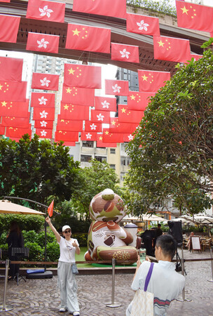 1日、中国への返還28年を迎えた香港で、中国国旗と香港旗の下で記念撮影する人たち