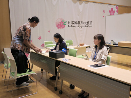 4日、北京の在中国日本大使館で在外投票を行う有権者(左)