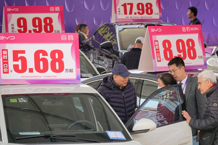 比亜迪(BYD)の電気自動車(EV)を見る自動車ショーの来場者=4月10日、中国山東省煙台(AFP時事)