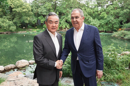 13日、北京で会談し、握手を交わす中国の王毅共産党政治局員兼外相(左)とロシアのラブロフ外相=ロシア外務省提供(AFP時事)