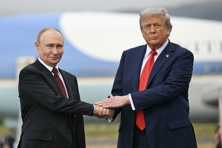 １５日、米アラスカ州アンカレジのエルメンドルフ・リチャードソン米軍基地に到着し、握手を交わすトランプ米大統領（右）とロシアのプーチン大統領（ＡＦＰ時事）