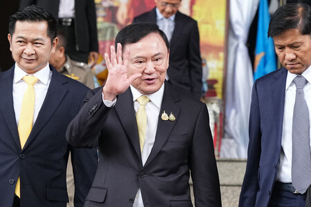 22日、バンコクの刑事裁判所を後にするタイのタクシン元首相(中央)(AFP時事)