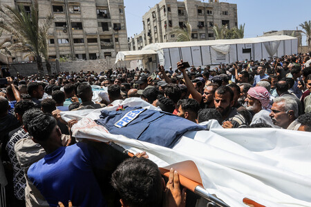 26日、パレスチナ自治区ガザ南部ハンユニスで、イスラエルによる病院攻撃の犠牲者遺体を搬送する住民(dpa時事)