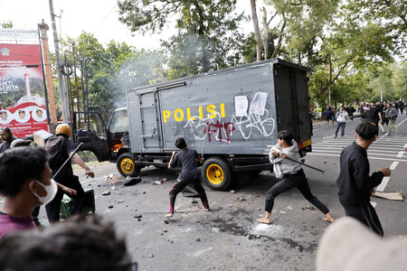30日、インドネシア・バリ島デンパサールで警察と衝突するデモ参加者(EPA時事)