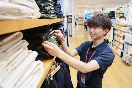 ユニクロで品出しを行う笹岡龍斗さん。スマホのメモ機能を使って接客も行う＝８月１４日、東京都江東区