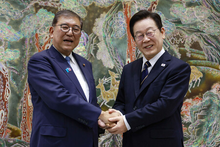 30日、韓国の釜山で李在明大統領(右)と握手する石破茂首相(AFP時事)
