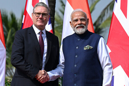 握手するインドのモディ首相(右)と英国のスターマー首相=9日、インド西部ムンバイ(AFP時事)