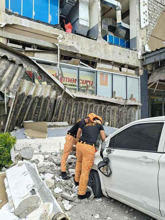 10日、フィリピン南部ミンダナオ島ブトゥアンで、がれきを取り除く消防隊員ら(フィリピン消防局提供)(EPA時事)