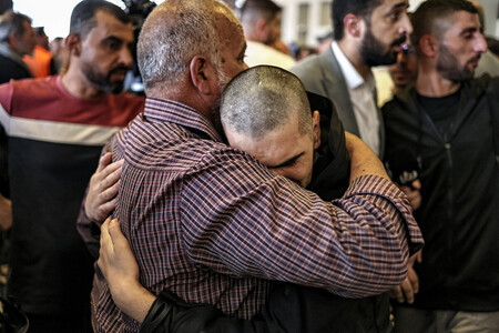 13日、イスラエルの刑務所から釈放され、パレスチナ自治区ラマラで父親と抱き合うパレスチナ人男性(右)(AFP時事)